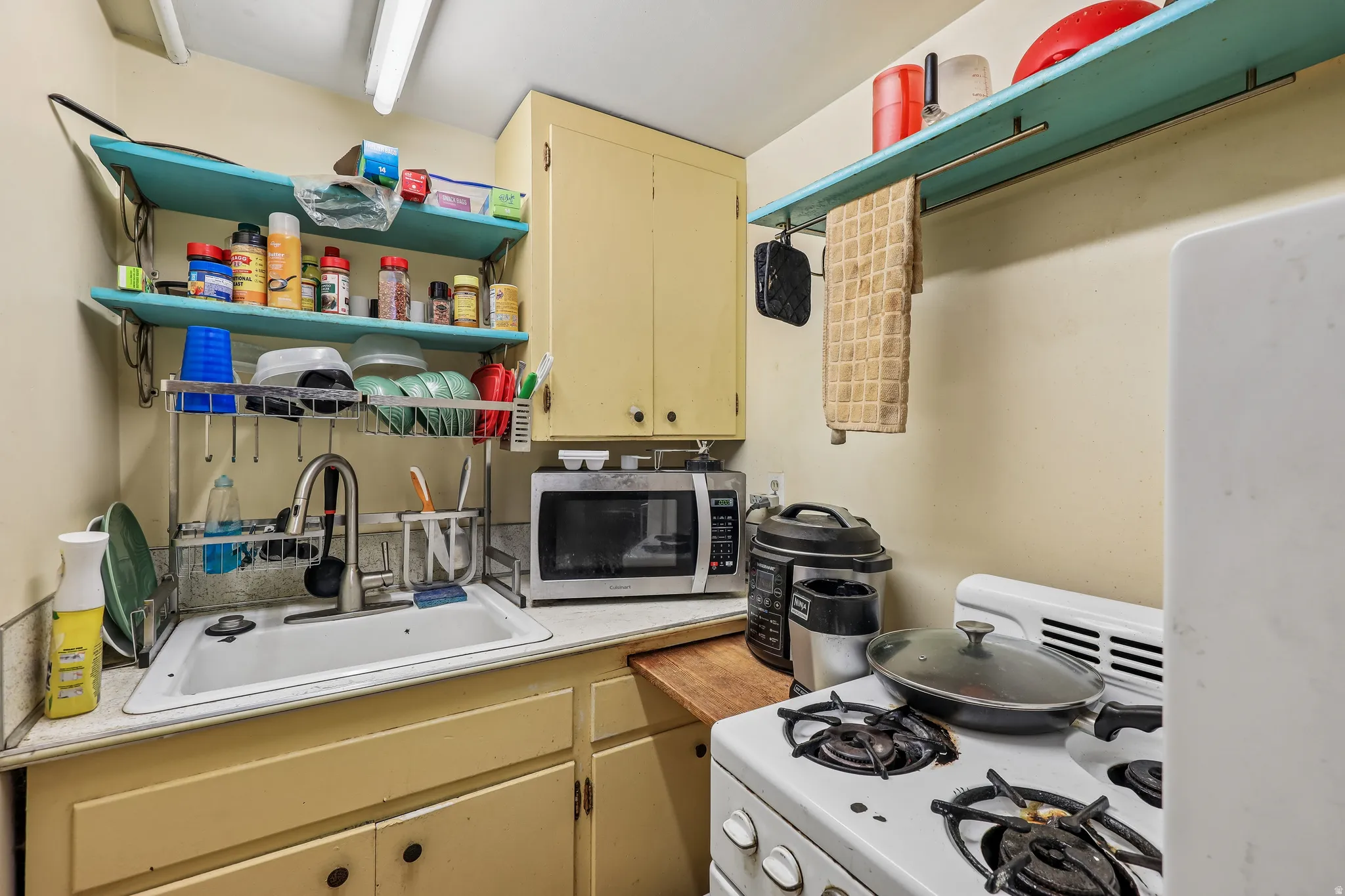 Compact kitchen featuring a gas range, single basin sink, and wood-finish countertop