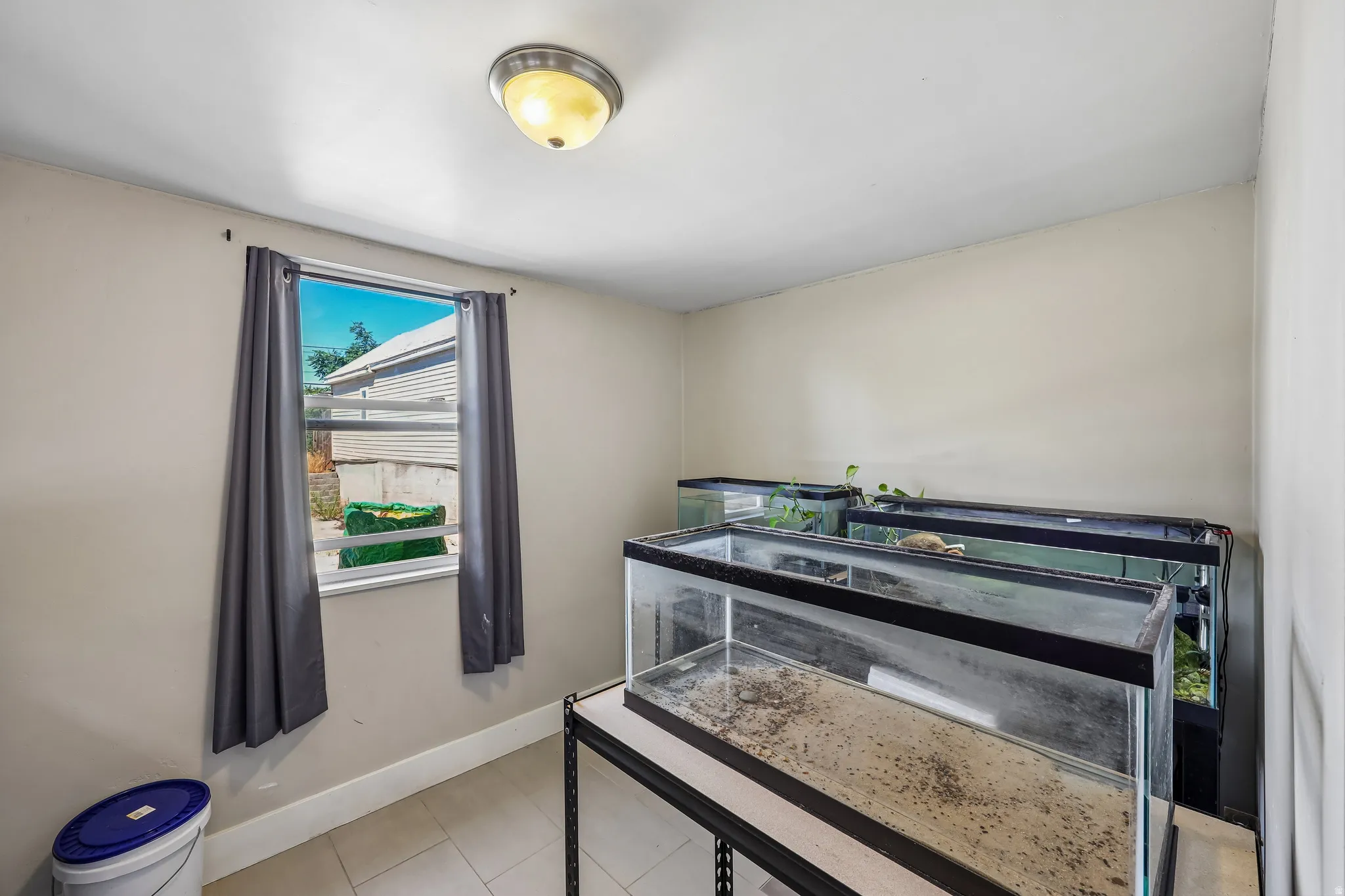Window with vertical blinds, light neutral wall paint, and overhead flush-mount lighting fixture