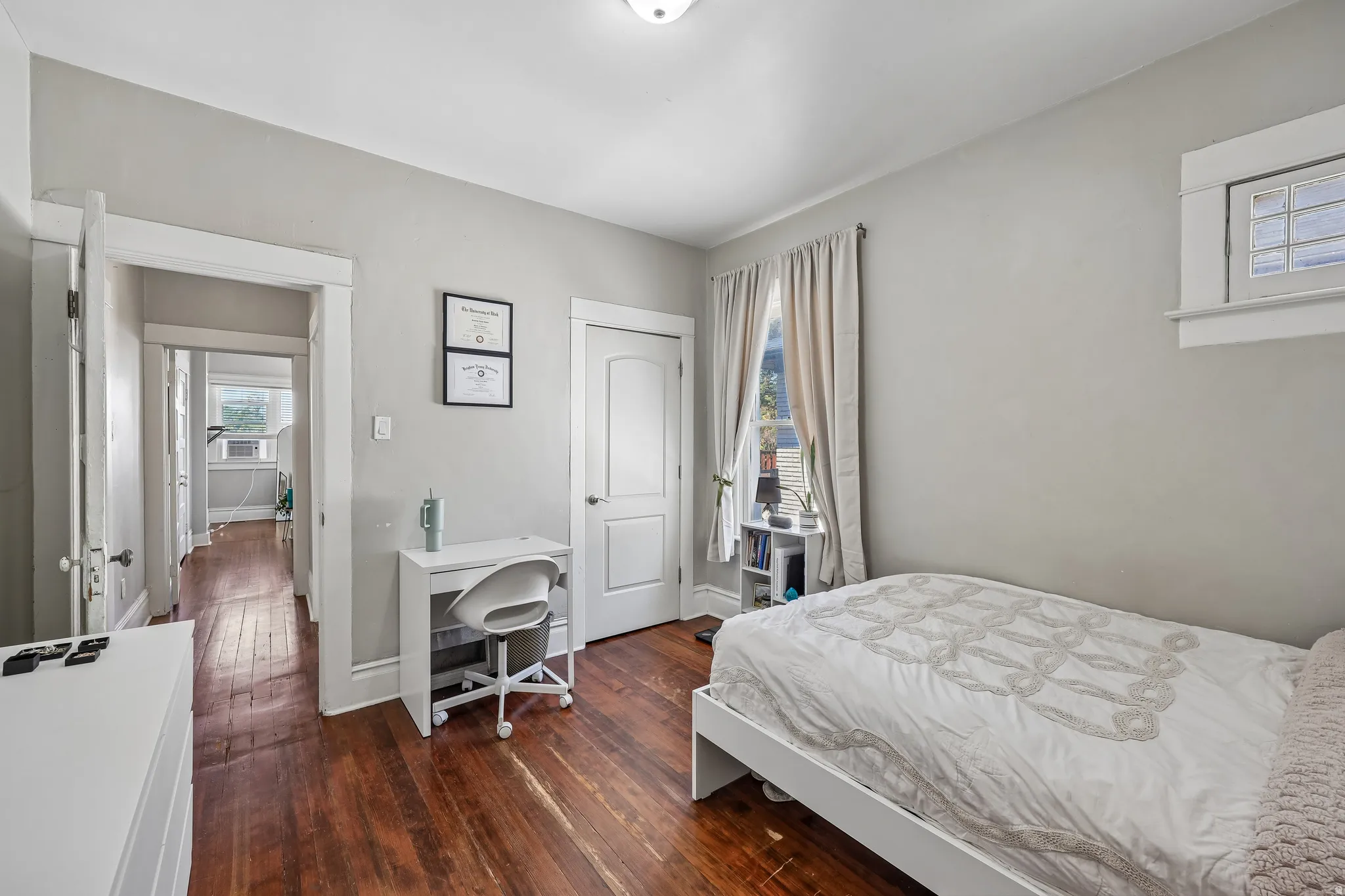 Hardwood flooring, painted walls, white trim, and a window with natural light