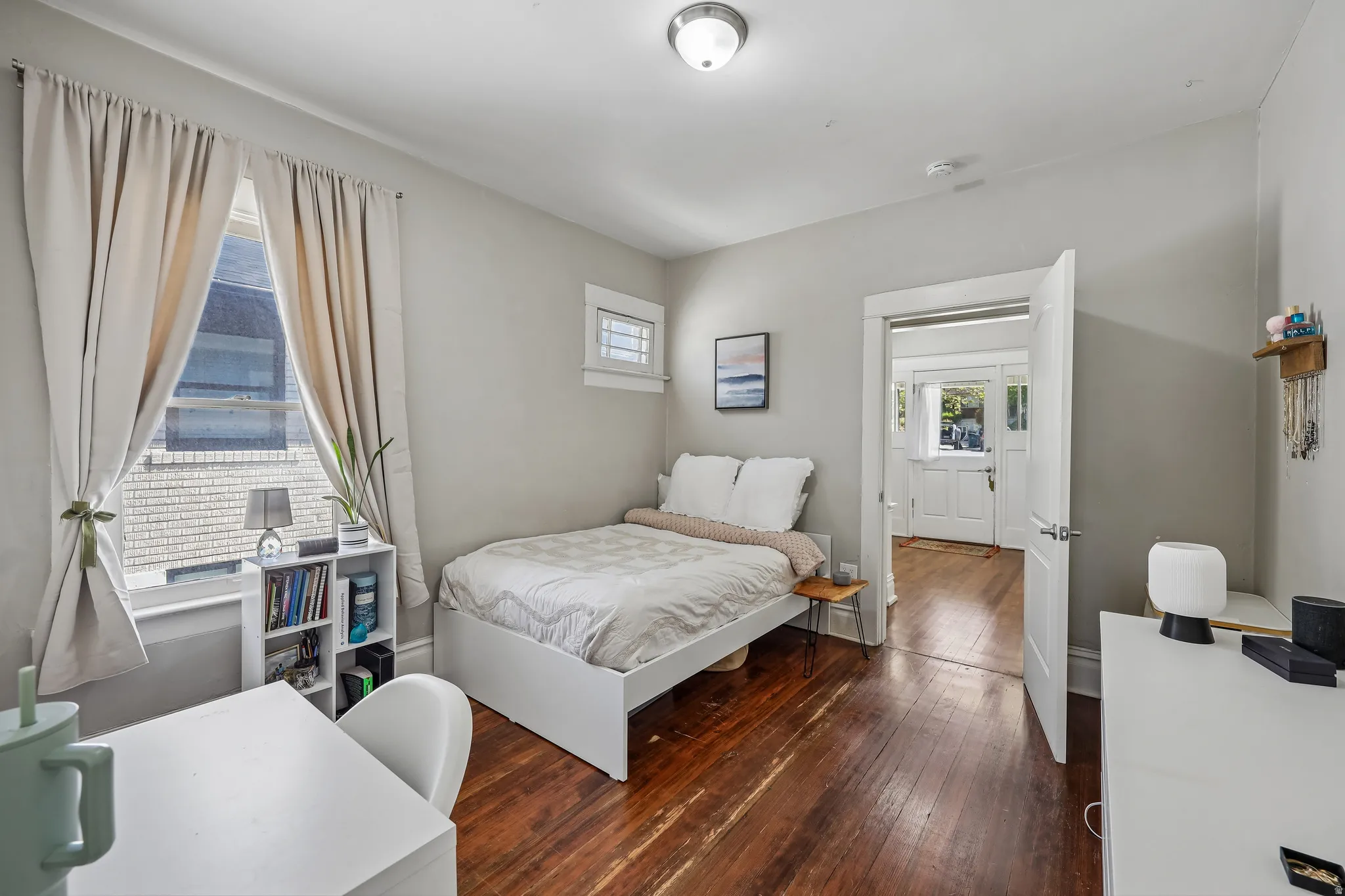 Hardwood flooring, painted walls, window with natural light, overhead ceiling fixture, white paneled door
