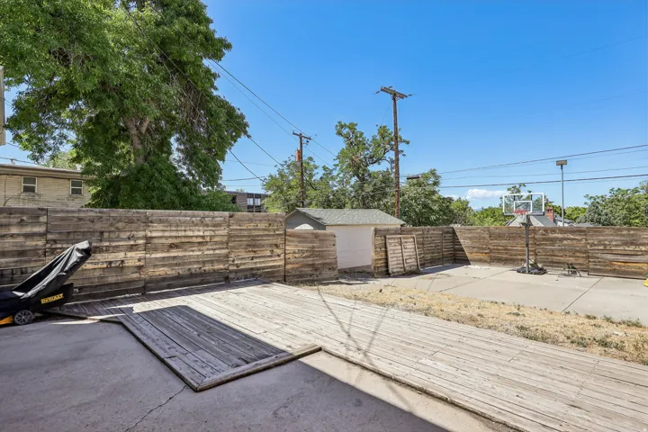Wood plank fencing enclosing a concrete patio area, featuring a standalone storage shed