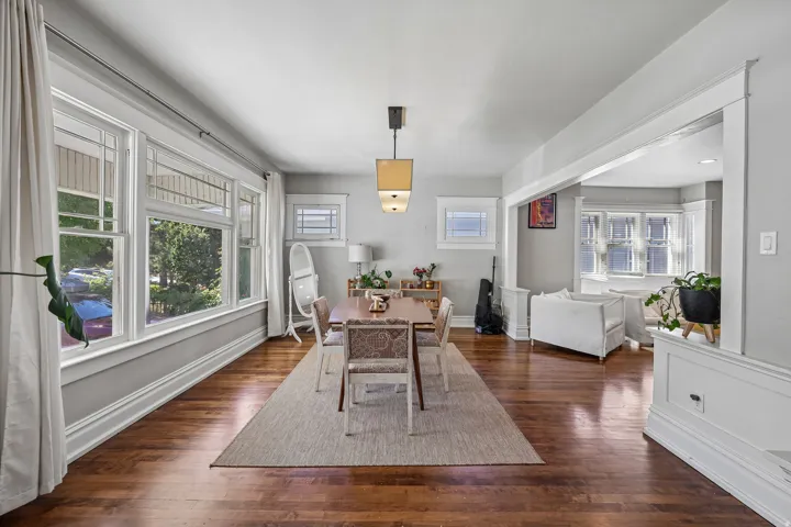 Hardwood flooring, recessed ceiling lighting, decorative trim work, multiple windows, and a doorway opening to an additional living space