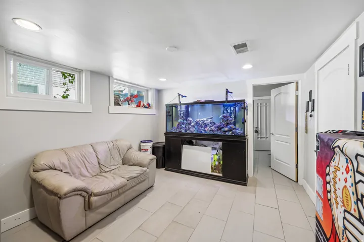 Recessed lighting throughout, two windows with white trim, light-toned floor tiles, and an arched panel interior door