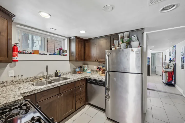 Kitchen featuring wood-finish cabinetry, granite-style countertops, and stainless steel appliances including a refrigerator and dishwasher
