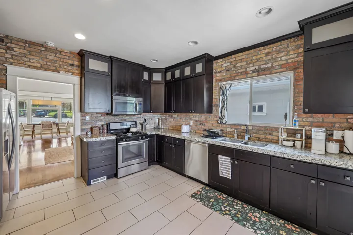 Kitchen featuring dark wood-finish cabinetry, stainless steel appliances, and light-toned tile flooring