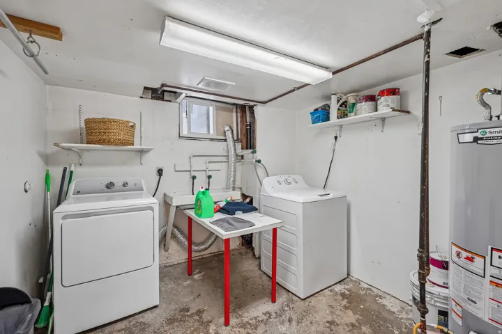 Laundry area featuring a utility sink, water heater, and overhead fluorescent lighting