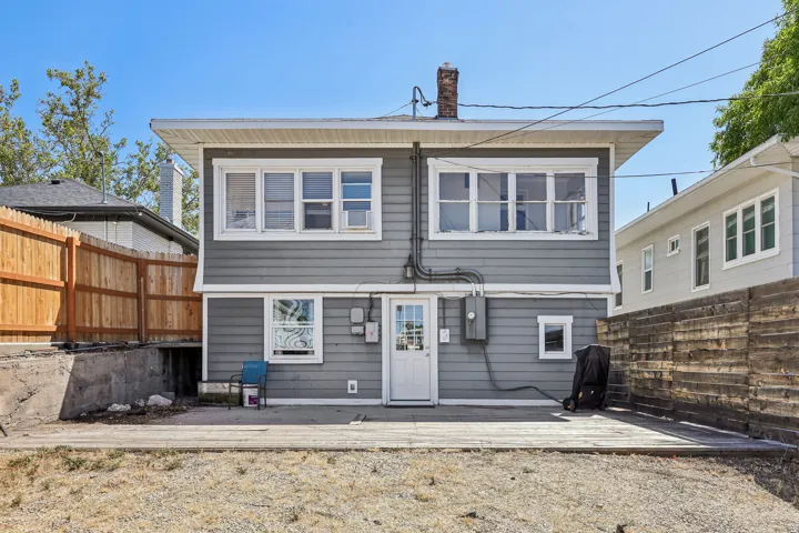Rear exterior featuring gray siding, multiple windows, and a white door with glass panels