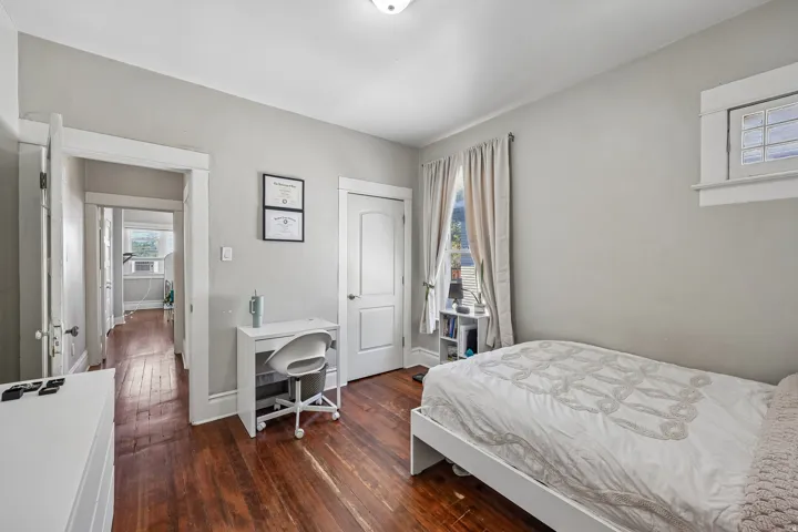 Hardwood flooring, painted walls, white trim, and a window with natural light