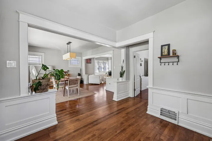 Hardwood flooring throughout, white trim and wainscoting, and a built-in wall shelf