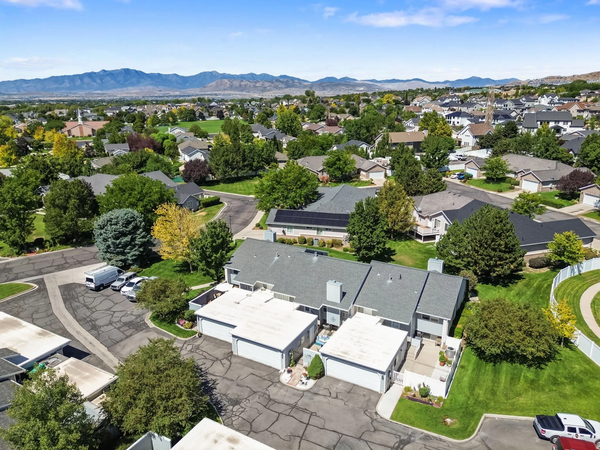Townhome property with gray siding, attached garages, and a paved driveway