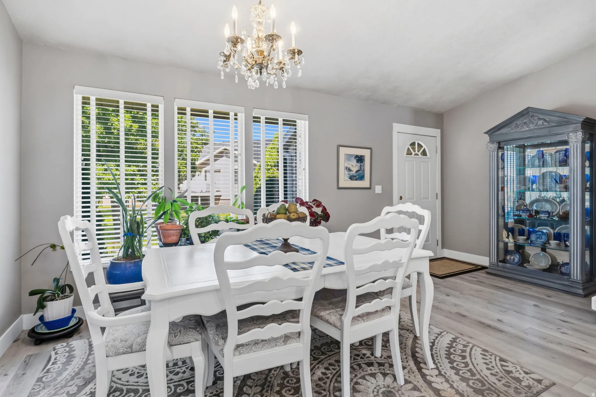 Vaulted ceiling, elegant chandelier, light gray walls, wood-finish flooring, and white trim