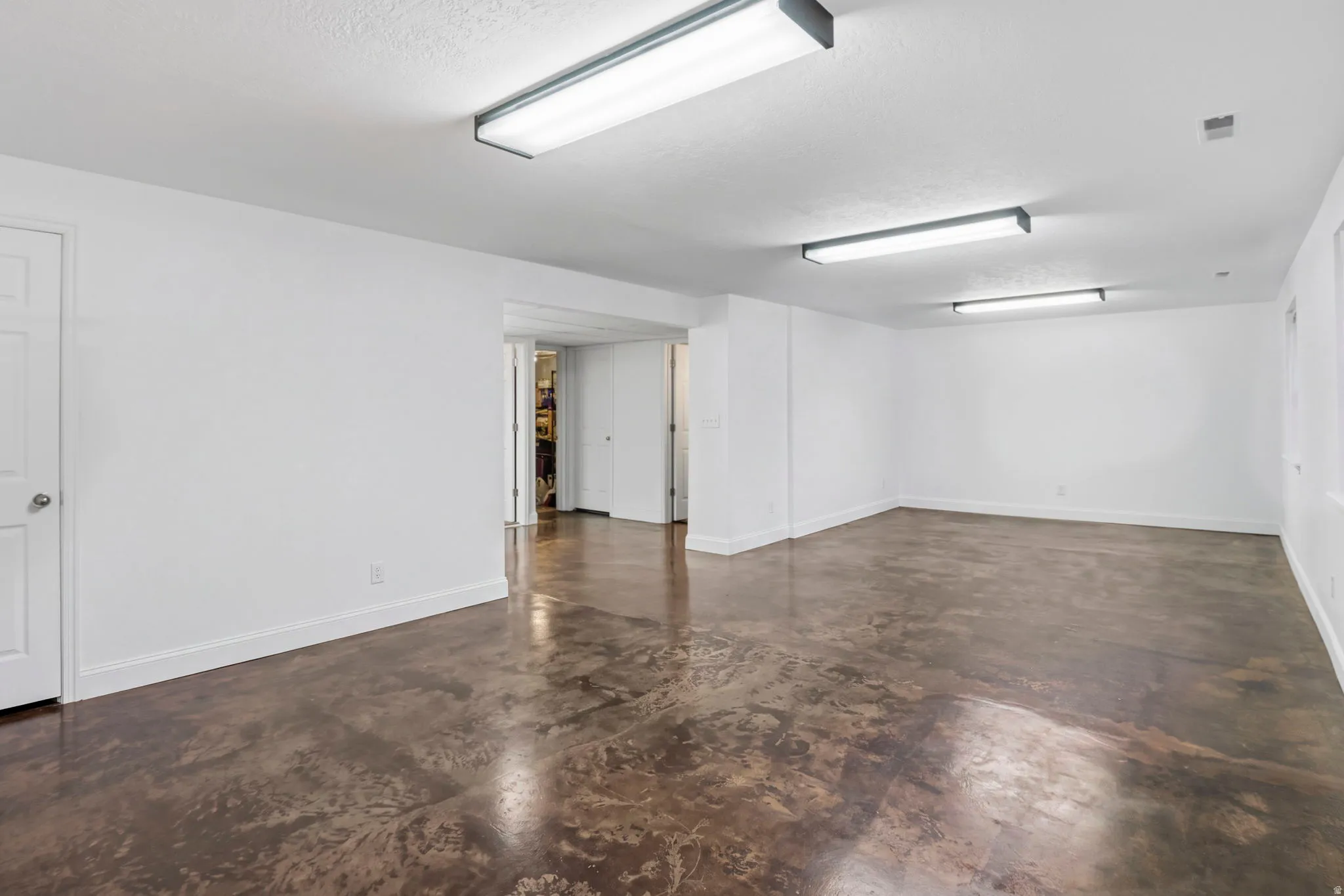 Spacious interior featuring a durable concrete floor, white walls, and bright overhead lighting