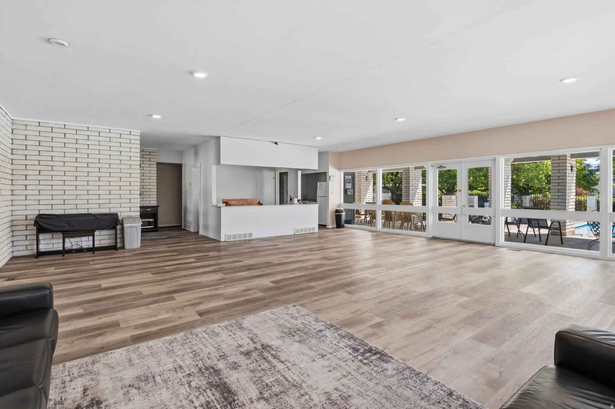 Expansive room featuring wood-finish flooring, a white brick accent wall, recessed lighting, and a built-in counter area