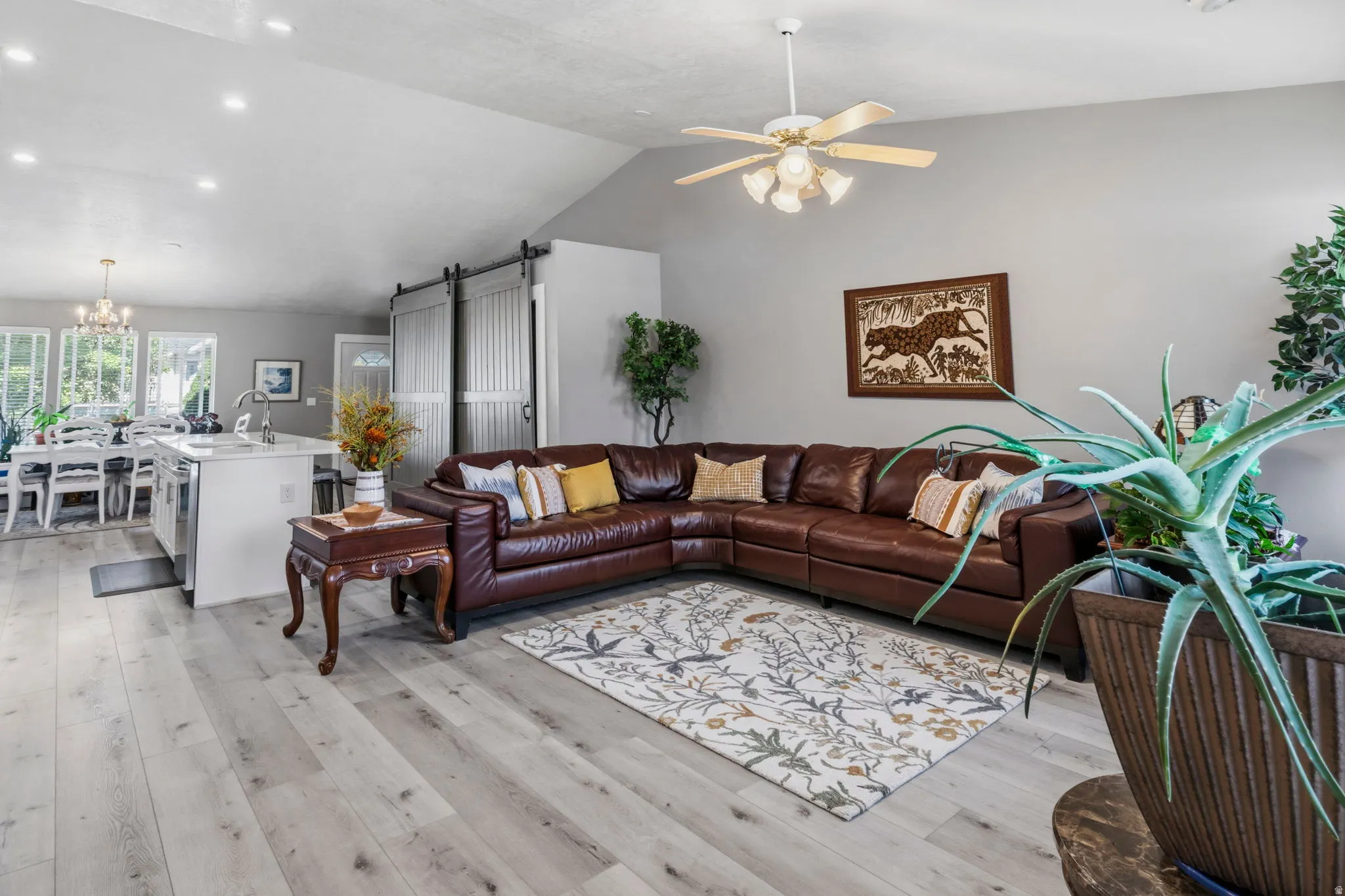 Vaulted ceiling, ceiling fan with integrated lighting, recessed lighting, wood-finish flooring, and barn doors
