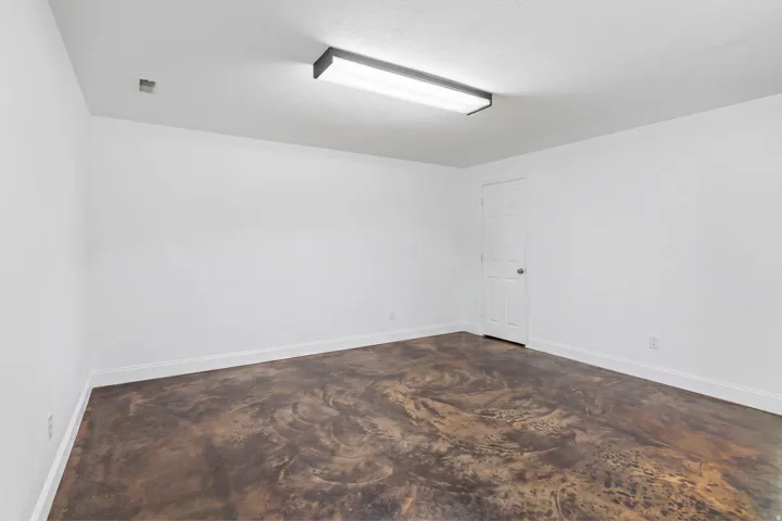 Smooth white walls with white trim, a flush-mount overhead light fixture, and a durable flooring surface