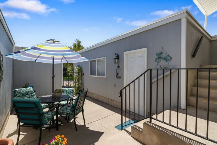 Private patio area with concrete flooring, exterior window, and concrete stairs with a metal railing