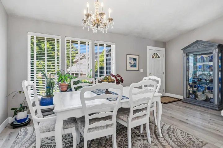 Vaulted ceiling, elegant chandelier, light gray walls, wood-finish flooring, and white trim