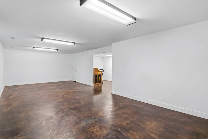 Expansive room featuring stained concrete flooring, bright overhead lighting, and white painted walls