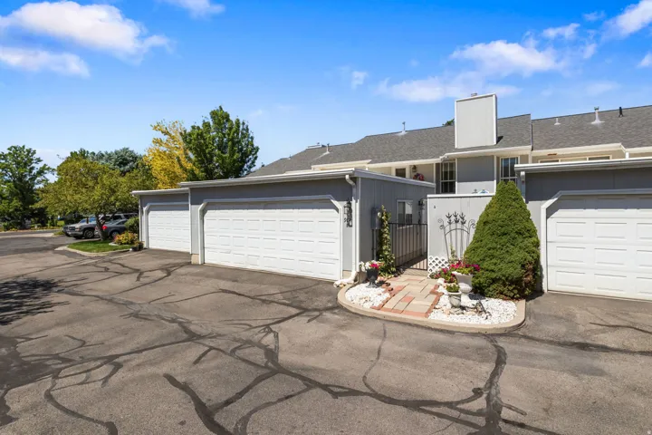 Attached single-car garages, grey siding exterior, paver walkway, and a decorative metal gate