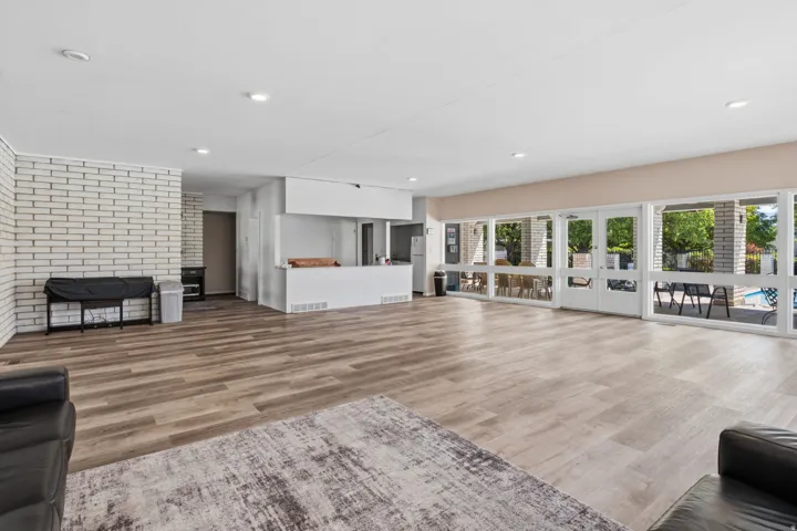 Expansive room featuring wood-finish flooring, a white brick accent wall, recessed lighting, and a built-in counter area