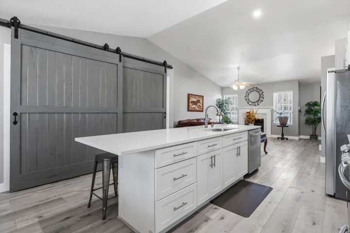 Kitchen island with white cabinetry, integrated sink, and light-toned countertop