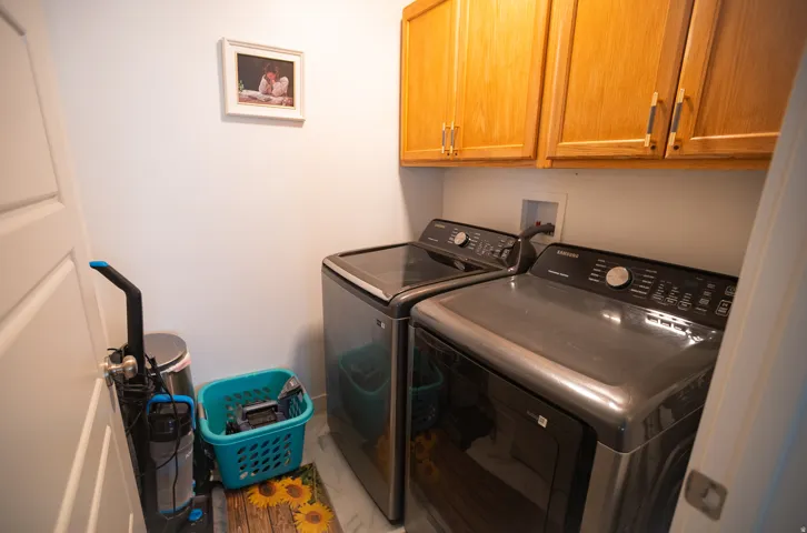 Laundry area featuring wood cabinetry, white walls, and a light-toned floor