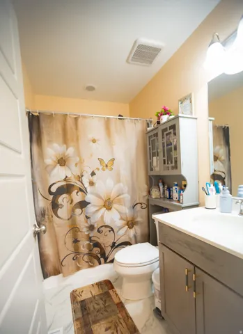 Vanity with an integrated sink and base cabinetry, wall-mounted light fixture, and white wall paneling