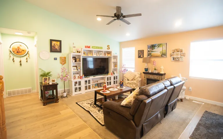Vaulted ceiling with a ceiling fan, recessed lighting, wood-finish flooring, and a built-in entertainment center