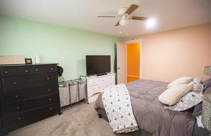 Carpeted flooring, ceiling fan with integrated lighting, and a white interior door