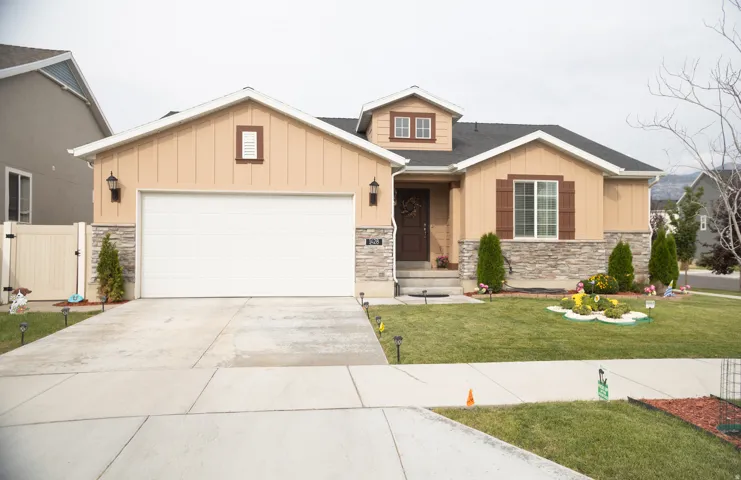 Single-story exterior with a two-car garage, stone facade accents, and a dormer window