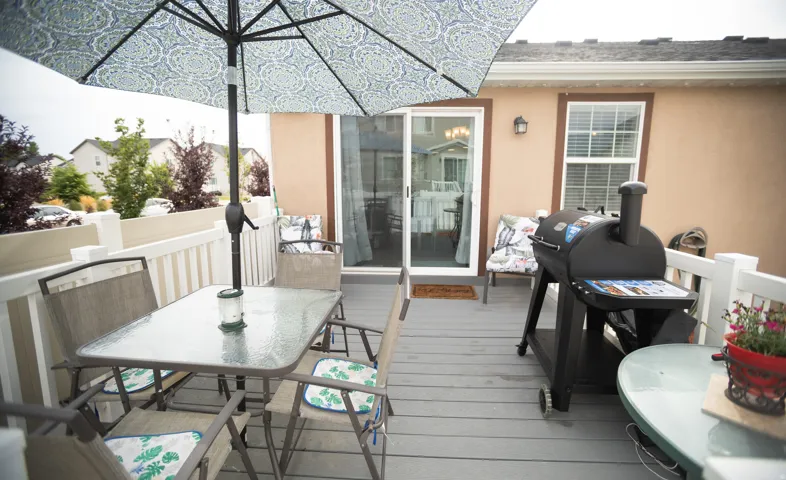 Spacious elevated deck with a durable composite surface, white railing, and exterior wall sconce