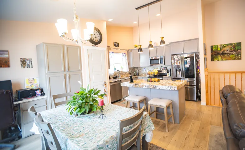 Kitchen featuring a multi-tone granite island with pendant lighting, stainless steel appliances, and gray cabinetry