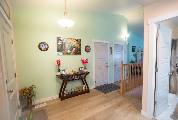 Vaulted ceiling, recessed lighting, wood-finish flooring, paneled interior doors, and a wood banister