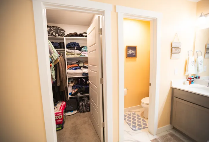 Built-in closet shelving, white interior doors, and a bathroom vanity with a white countertop