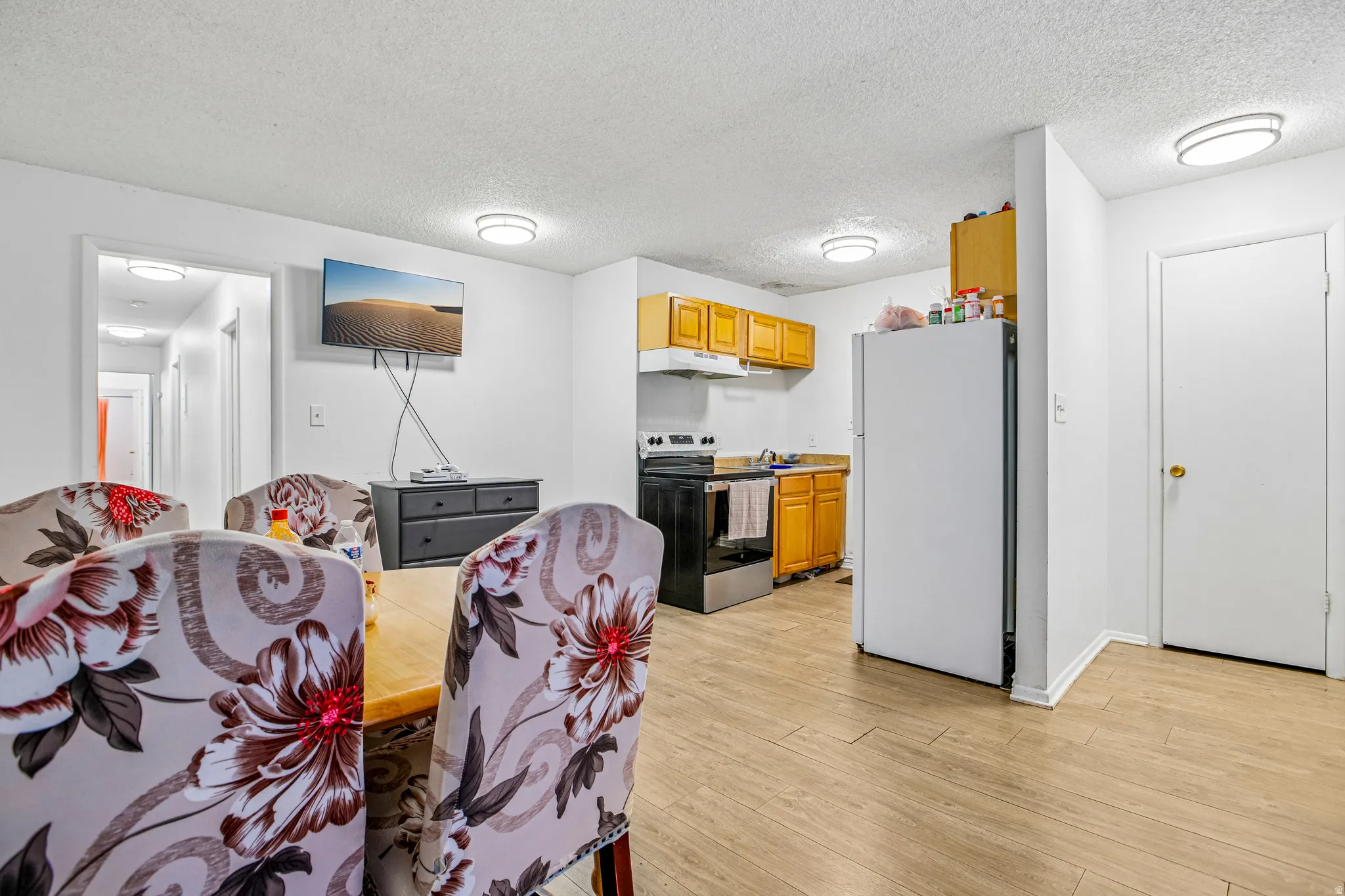 Kitchenette featuring wood-finish flooring, wood cabinetry, and white appliances