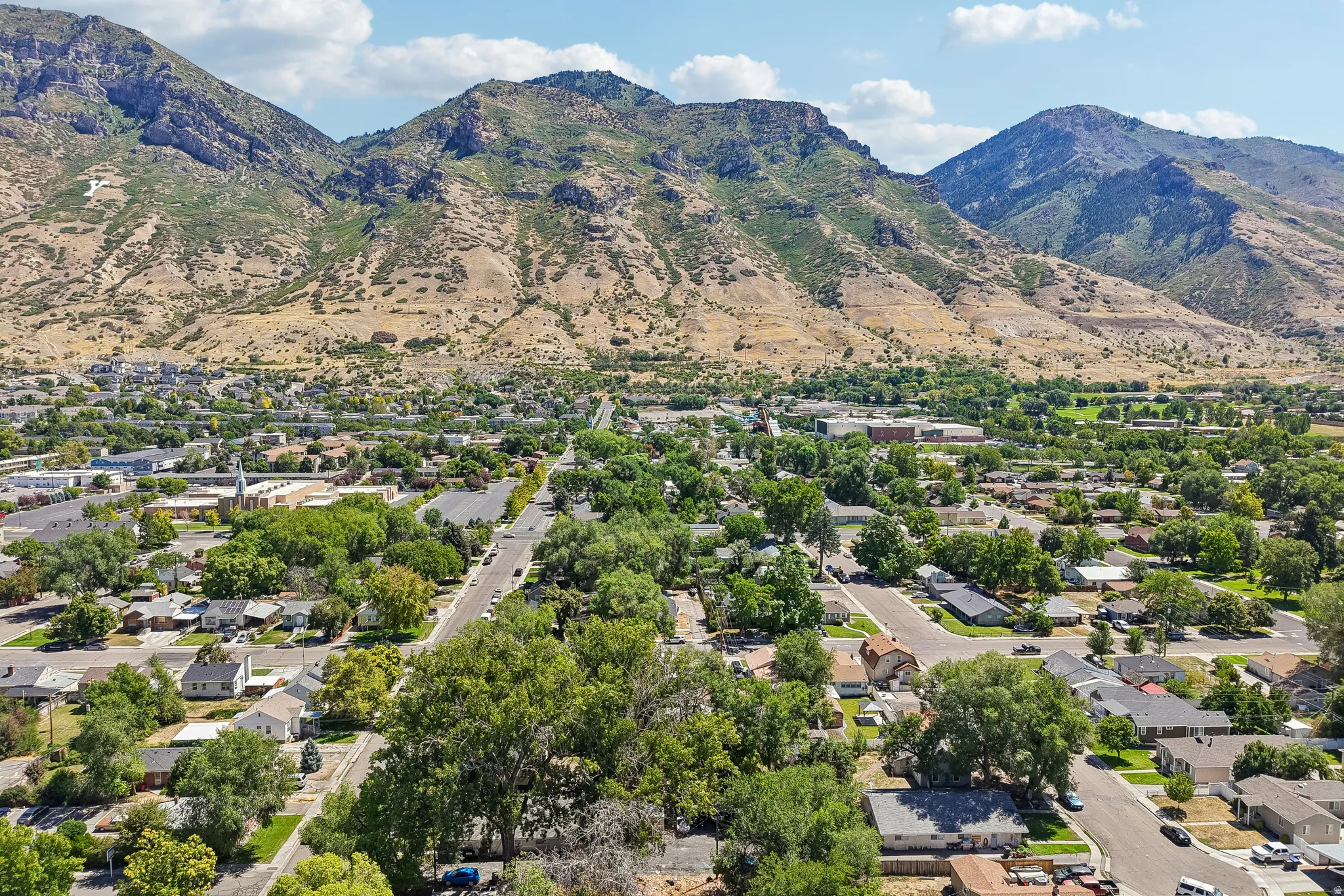 Expansive mountain backdrop with a developed residential area featuring mature trees and a clear sky