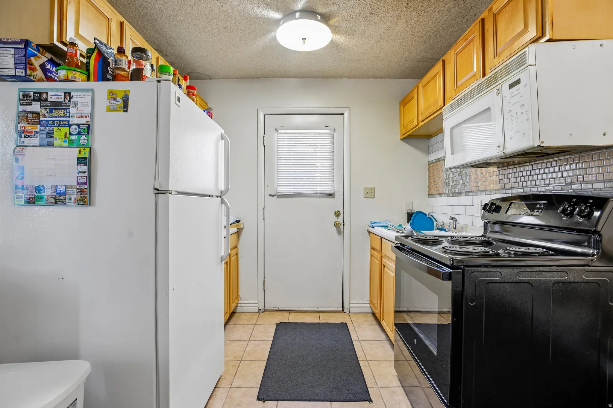 Kitchen featuring wood-finish cabinetry, tile flooring, and integrated black stove