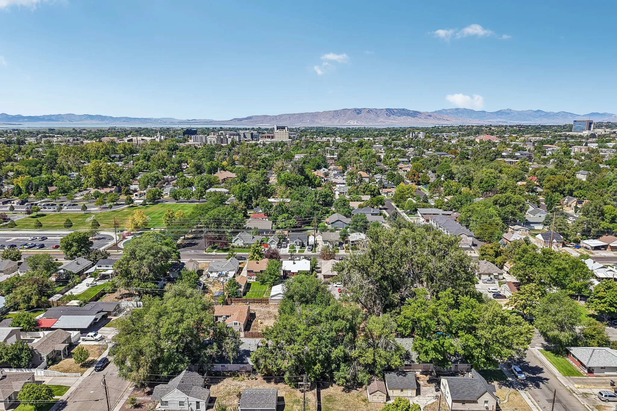 Aerial perspective of the surrounding residential area featuring established green spaces and distant mountain ranges