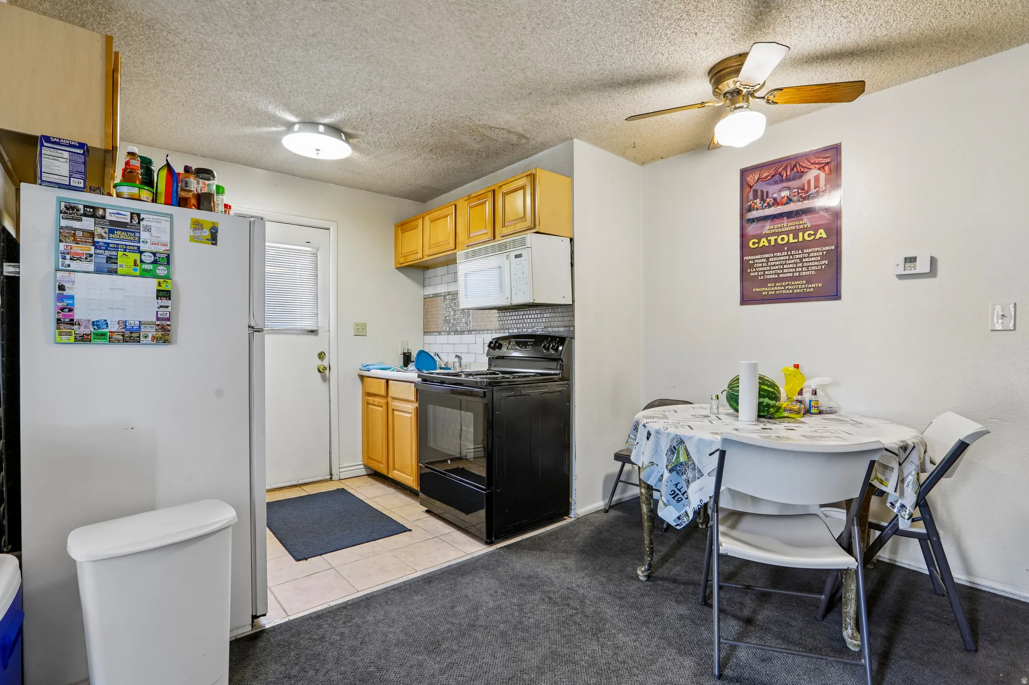 Kitchen featuring wood-finish cabinetry, a tile backsplash, and a white refrigerator