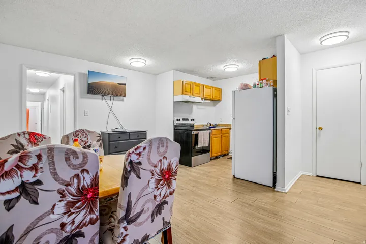 Kitchenette featuring wood-finish flooring, wood cabinetry, and white appliances