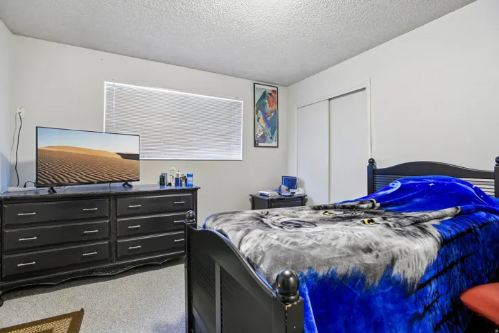 Window with horizontal blinds, built-in sliding closet, and textured ceiling