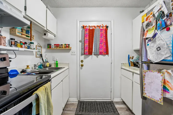 White cabinetry, wood-finish flooring, and white countertops