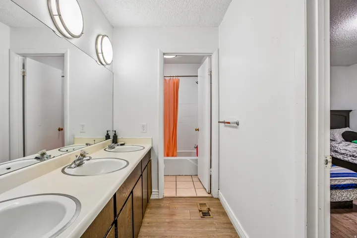 Dual vanity with integrated sinks, full-width mirror, and overhead lighting