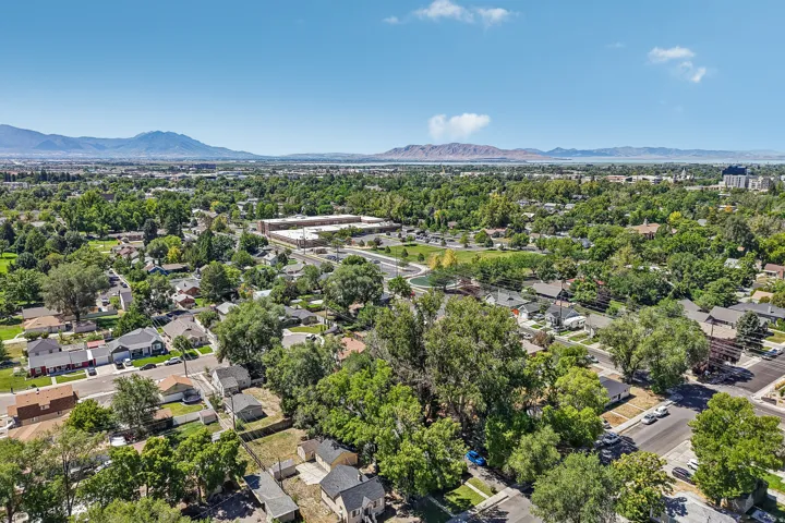 Expansive urban landscape featuring mature trees, residential properties, and distant mountains