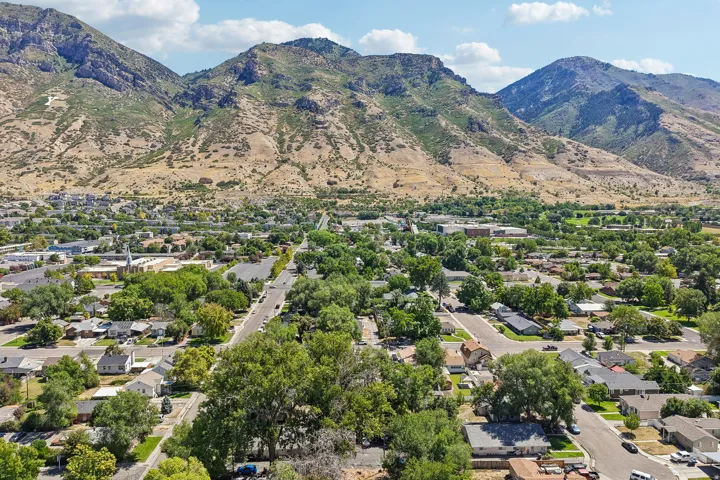 Expansive mountain backdrop with a developed residential area featuring mature trees and a clear sky