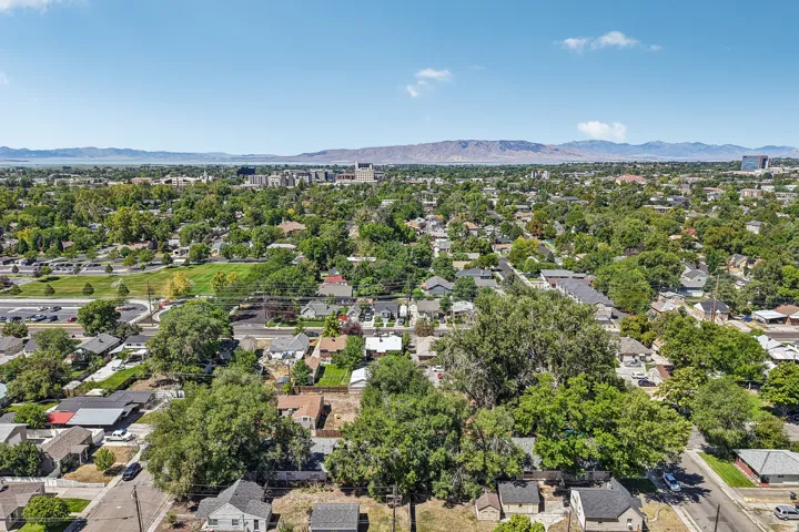 Aerial perspective of the surrounding residential area featuring established green spaces and distant mountain ranges