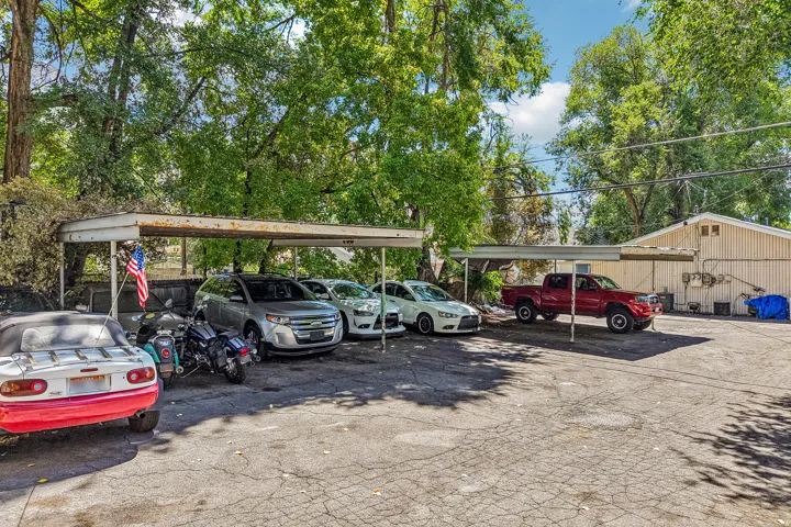 Expansive paved parking area featuring multiple carport structures and mature trees