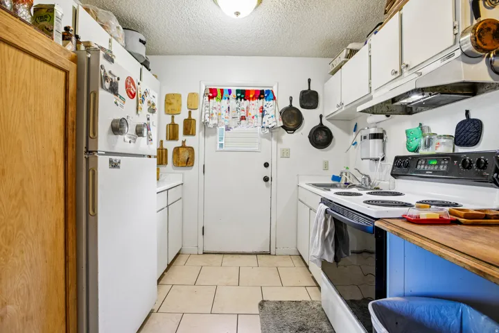 White kitchen cabinetry, white refrigerator, and white electric range