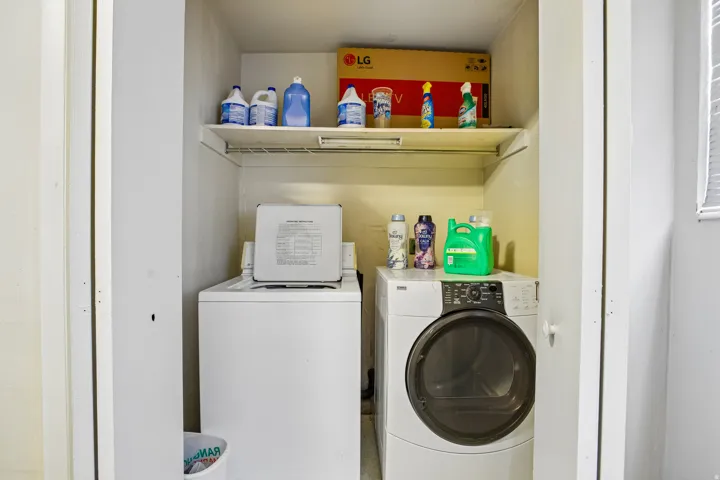 Closet laundry area featuring a top-load washing machine, front-load dryer, and a wire storage shelf