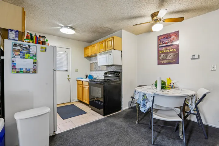 Kitchen featuring wood-finish cabinetry, a tile backsplash, and a white refrigerator